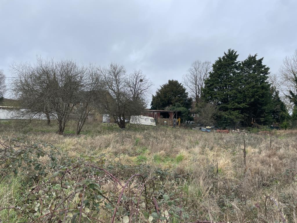 Lot: 98 - LAND EXTENDING TO TWO-THIRDS OF AN ACRE WITH PLANNING FOR REPLACEMENT STORAGE BUILDING - View across land with barn for redevelopment